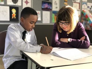 Boy at desk being tutored by woman